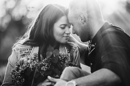 Close up profile portrait of an attractive young couple on holiday being romantic and kissing while relaxing during a summer break vacation. Love and relationships outdoors. Black and whiteの写真素材