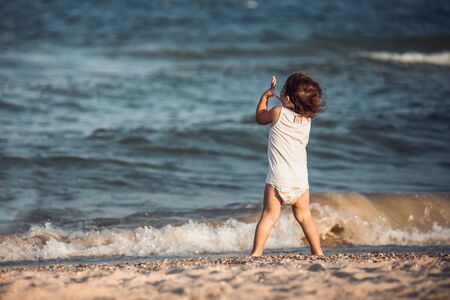 Silhouette of child on the beach, holding his hands upの写真素材