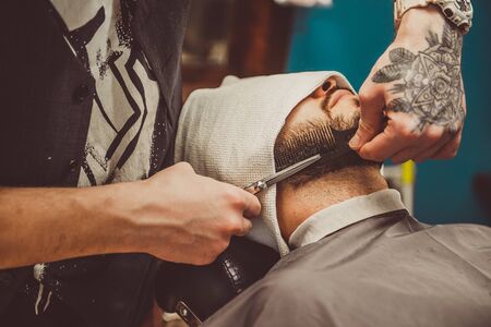 Cropped closeup of a young man having his beard shaped in a barbershop
