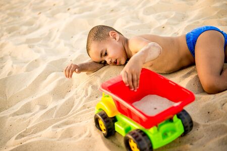 little black boy playing on beach summer toy machineの写真素材