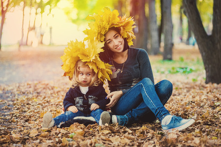 Young mother playing with her daughter in autumn parkの写真素材