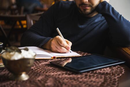 Young business man writing at the notebook outside office table work space,close up and selective...