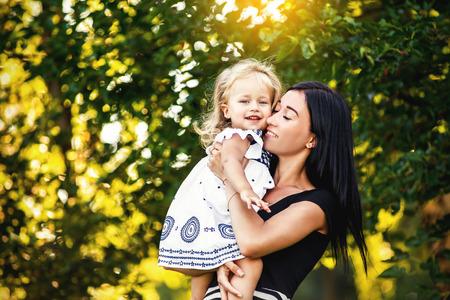 mom throws up and kisses her daughter in the Parkの写真素材
