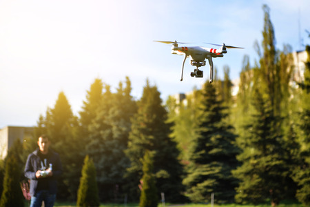Man controls a quadrocopter. Selective focus on drone, men is blurred. Launching a quadrocopter in...