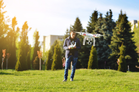 Man controls a quadrocopter. Selective focus on drone, men is blurred. Launching a quadrocopter in...