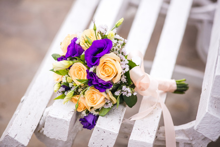 Wedding bouquet of roses and purple on white benchの写真素材
