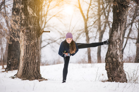 Fit woman athlete doing left leg split stretching exercises outdoors in woods. Female sports model...