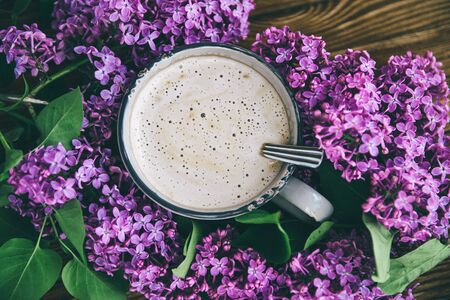 Coffee Cup on a background of lilac, wooden table. A cup of cappuccino is held by a handの写真素材