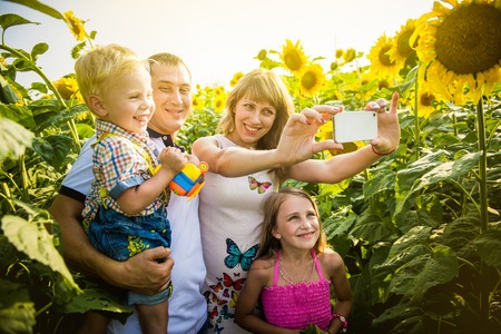 Happy family with two children in sunflower field. Photographed by phone, Selfieの写真素材