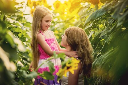Happy mother and her daughter in the sunflower field. Summer funの写真素材