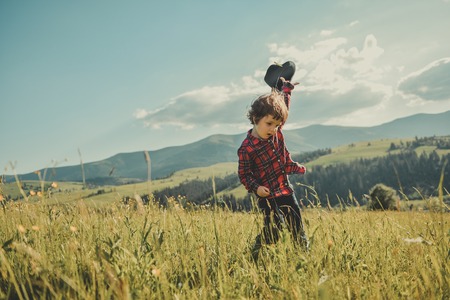 Happy little boy running over the top of the mountain. A child with a hat in his hand on a hill of the mountain. Carpathian mountainsの写真素材