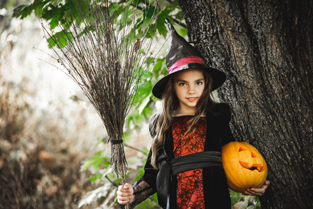 Happy Halloween. Cute little witch with a pumpkin in the hands.の写真素材