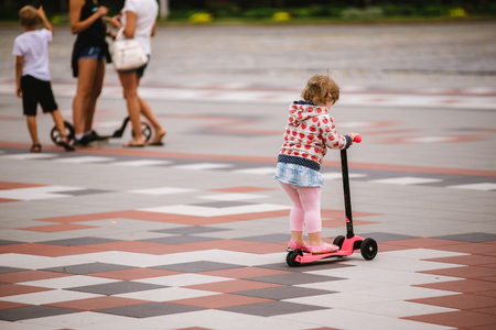 little beautiful girl riding scooter at stadiumの写真素材