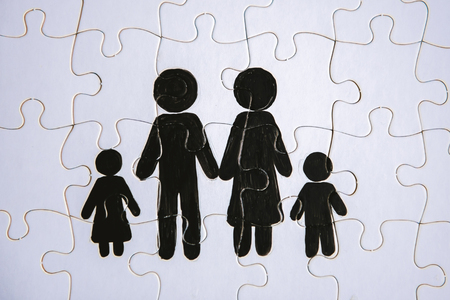 Family concept, puzzle. Father, mother, son and daughter painted on a puzzleの写真素材