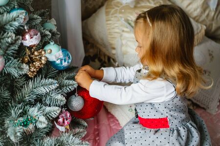 Little girl decorating Christmas tree with glass ballsの写真素材