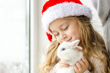 little girl in white dress with a little girl in red dress sitting by the window waiting for Christmas and Santa Clausの写真素材