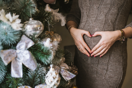 Pregnant belly, hugging the stomach and hands in the shape of the heartの写真素材