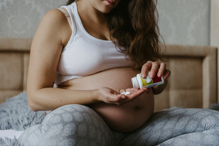 Closeup of pregnant woman's hand with pills. Consumption of pregnant calcium, vitamins.の写真素材