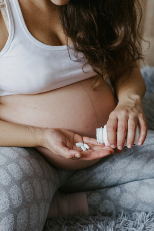 Closeup of pregnant woman's hand with pills. Consumption of pregnant calcium, vitamins.