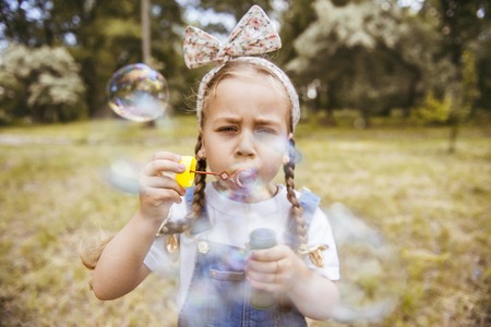 Cute little girl is blowing a soap bubblesの写真素材