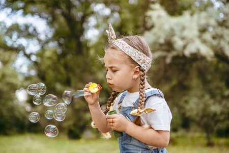 Cute little girl is blowing a soap bubblesの写真素材