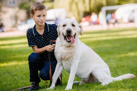 Portrait of cute adorable little Caucasian baby boy sitting with dog in park outside. Smiling child...