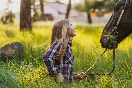 Young blonde girl stroking a brown horse.の写真素材