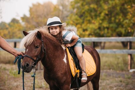 Adorable little girl riding a pony at summerの写真素材