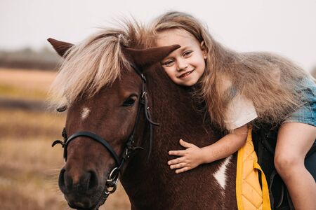 Adorable little girl riding a pony at summerの写真素材