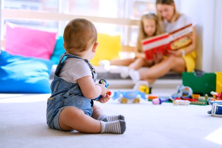 Learning at home. Happy family mother child daughter little girl reads a book by the window. Mother on maternity leave with two children.の写真素材
