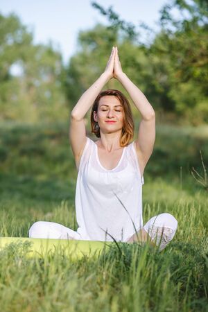 A girl is meditating under a tree. Yoga classes in natureの写真素材