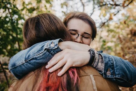 Charming young women kissing gently loving each other stroking touching face skin enjoying romantic tender moments on picnic date in the countryside.の写真素材