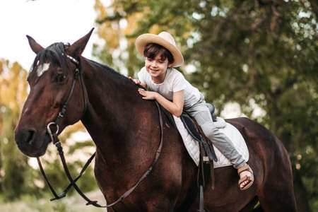 Boy with hat riding a horse outdoors. Pet therapy