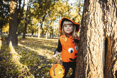 Happy Halloween! Cute little witch with a basket in the park