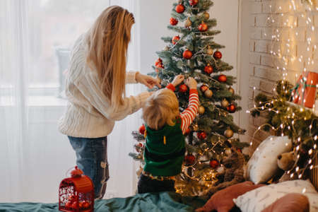 happy mother and cute little son decorating christmas tree togetherの写真素材