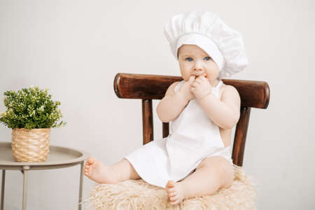 Little boy in cook clothes sits on a high chair on a white backgroundの写真素材