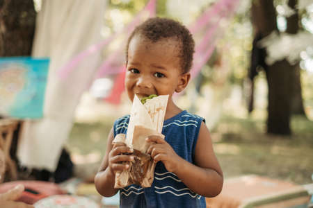Little black African American boy hungry eating bread.