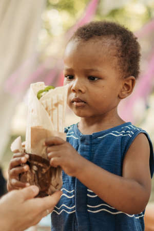 Little black African American boy hungry eating bread.の写真素材