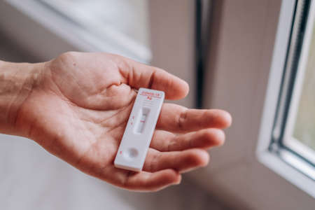 covid 19 negative result rapid test, Coronavirus self testing at home, Man hand holding kit for detecting antibodies and immunity. Closeup view, selective focusの写真素材