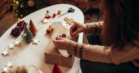 Woman s hands wrapping Christmas gift boxes, close up. Unprepared presents on white table with decor elements and items Christmas or New year DIY packing Concept.の写真素材
