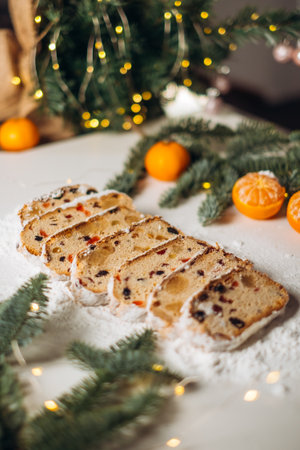 Traditional Christmas stollen, sliced and dusted with powdered sugar, filled with candied fruit, raisins, and nuts. A festive atmosphere, a warm and cozy winter mood.の写真素材