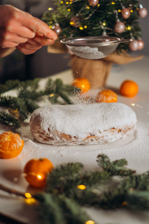 Traditional German Christmas stollen is dusted with powdered sugar through a sieve. The atmosphere is cozy, festive, and warmの写真素材