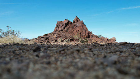 Volcanic rock formation showing iron oxide weathering in a dry desert environment with clear blue sky.  Igneous rock outcrop with oxidation in arid desert terrain.の写真素材