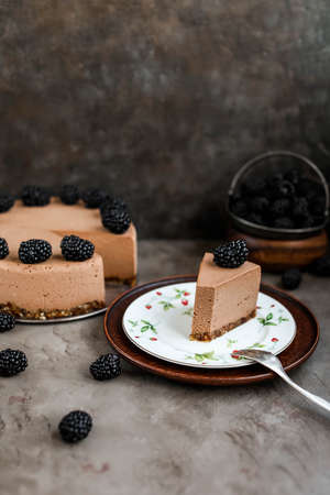 Chocolate mousse cake with blackberries on a high wooden stand. Lots of berries. Still life.の写真素材