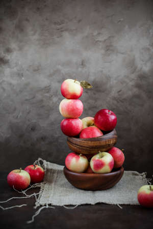 Lots of small apples in wooden bowls. Autumn harvest of fruits on a dark background.の写真素材
