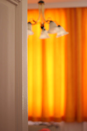 A room in an old building with orange curtains and a ceiling lampの写真素材