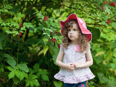 Little girl in a red cap standing in the woodsの写真素材