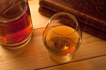 glass with cognac bottle and booksの写真素材