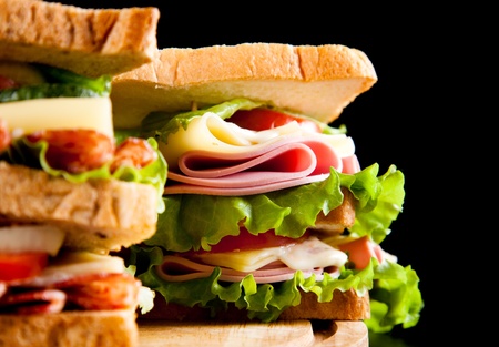 big sandwich with fresh vegetables on wooden board black backgroundの写真素材