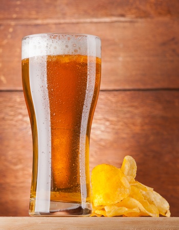 glass of fresh golden beer with potato chipsの写真素材